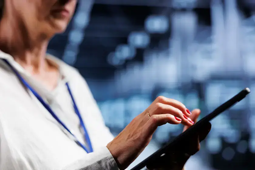 Woman using a tablet in a technology-focused environment, illustrating digital solutions for cybersecurity and IT management.