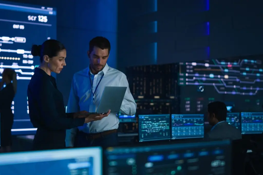 Benefits of Managed IT Services – Managed IT Services, Consulting, and Support for Businesses and Non Profits Professionals discussing managed IT services in a high-tech control room with multiple screens displaying data and analytics.